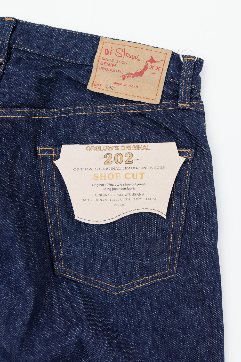 Close-up back view of dark indigo selvedge denim jeans showing the back pocket and brand tags.