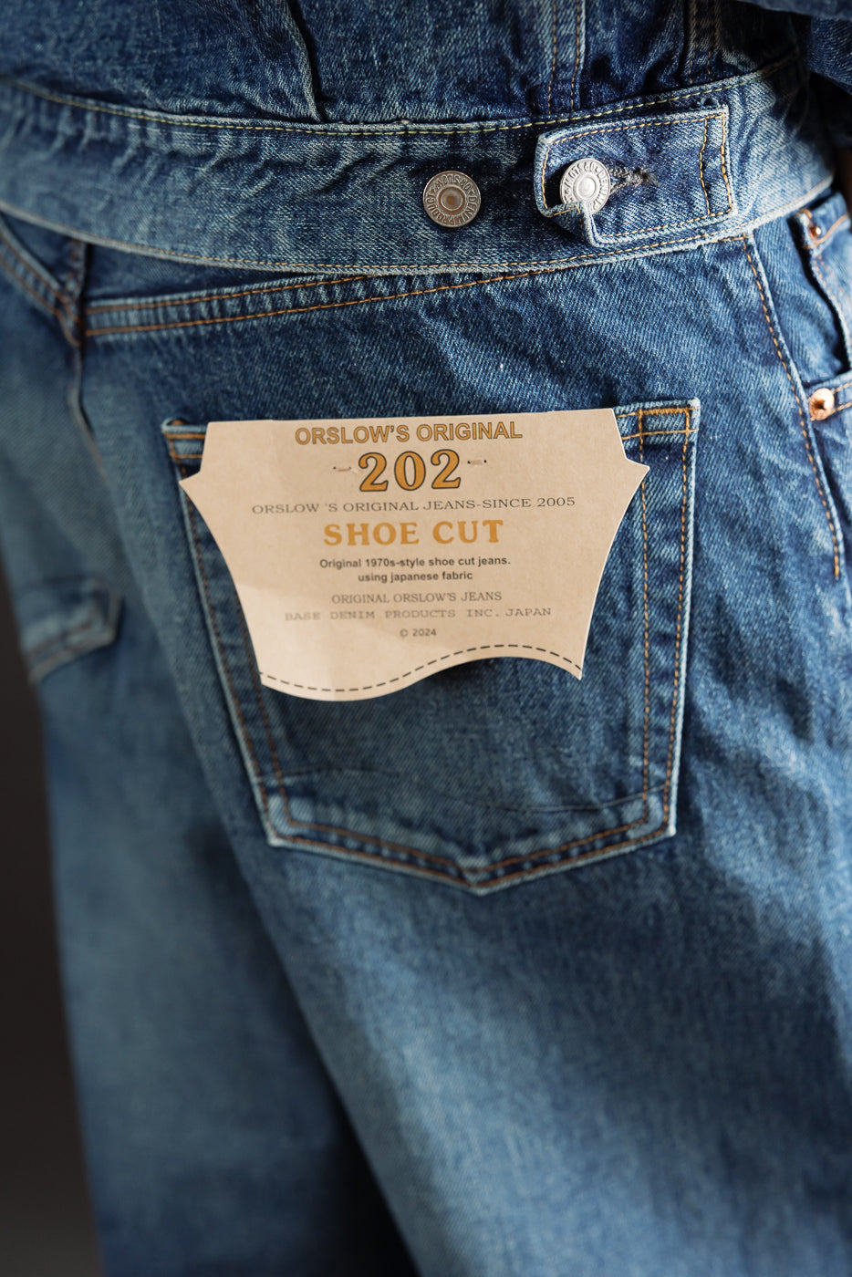 Close-up of the back right pocket of blue denim jeans featuring a tan Orslow's Original patch.