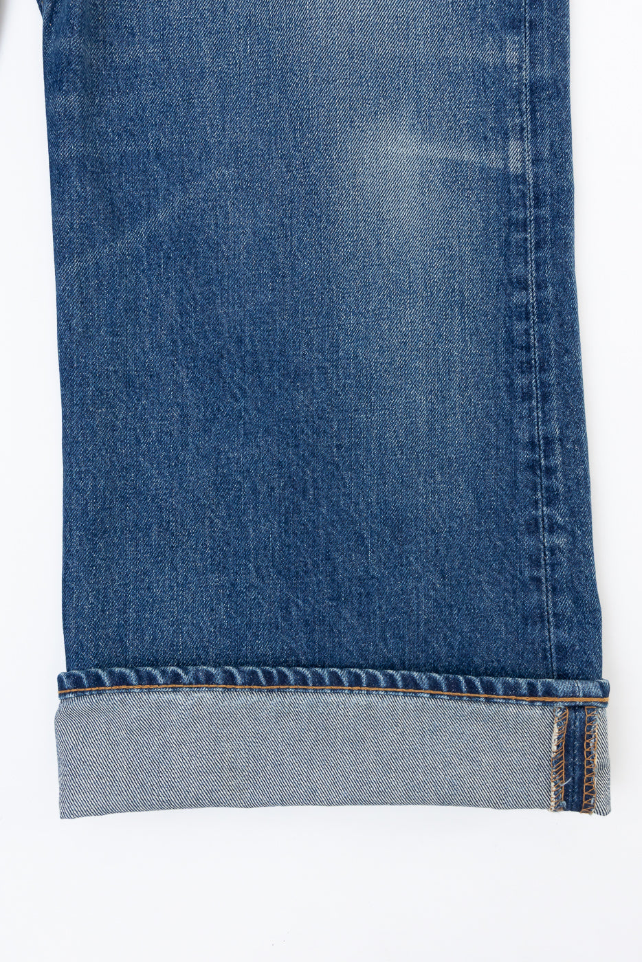 Close-up front view of cuffed blue denim jeans showing fabric texture and selvedge edge.