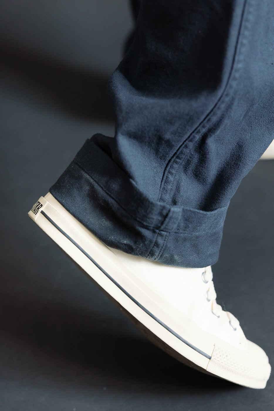 Close-up of cuffed Orslow fatigue pants brushed flannel, dark navy, lower hem side view on male model, showing fabric texture above white sneaker.