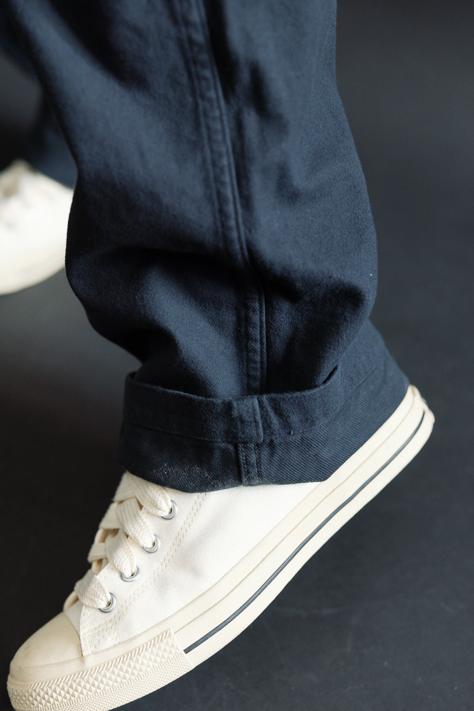Close-up of orSlow fatigue pants in dark navy brushed flannel, cuff and hem detail, side view, on athletic male model, Dant store.
