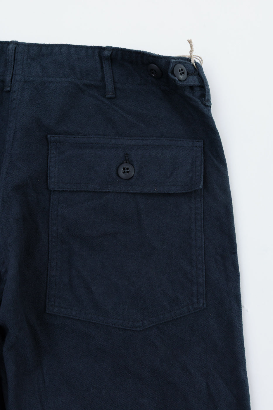 Close-up of orSlow dark navy brushed flannel fatigue pants, back side, showing buttoned pocket and waistband details.