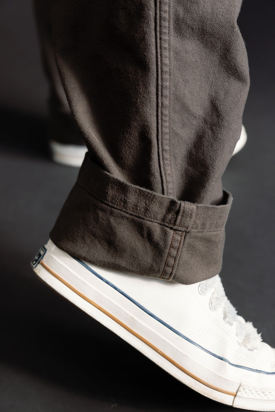 Close-up of coffee brown brushed flannel fatigue pants hem, side view, cuffed at ankle on male model, 5'9