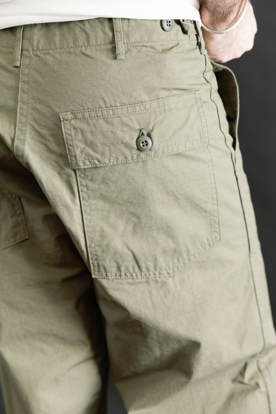 Close-up rear view of army green ripstop fatigue pants pocket on male model, 5'9