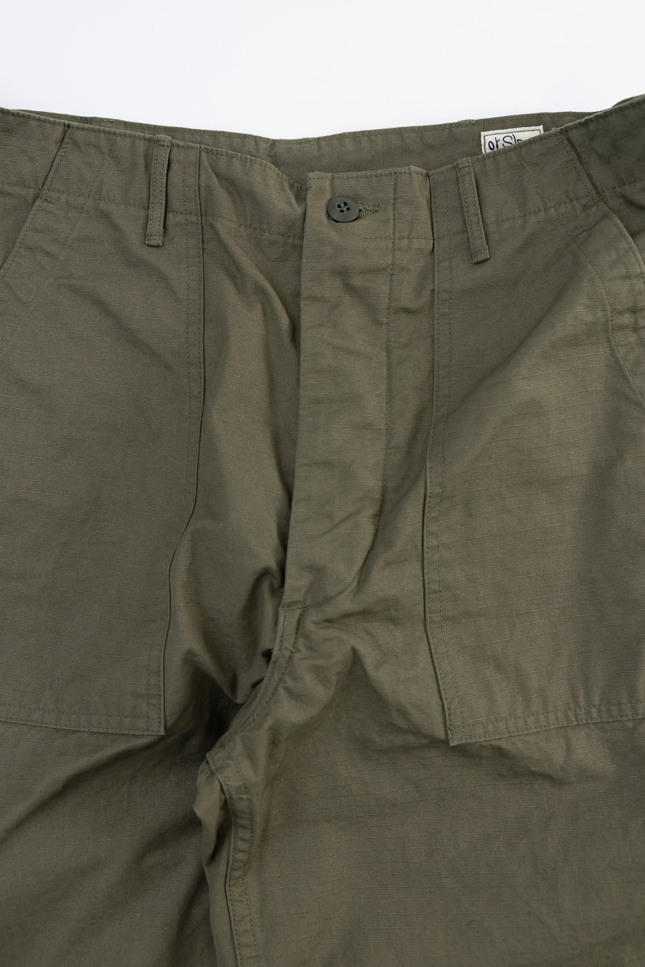Close-up front view of army green ripstop fatigue pants waist, button, and pockets detail