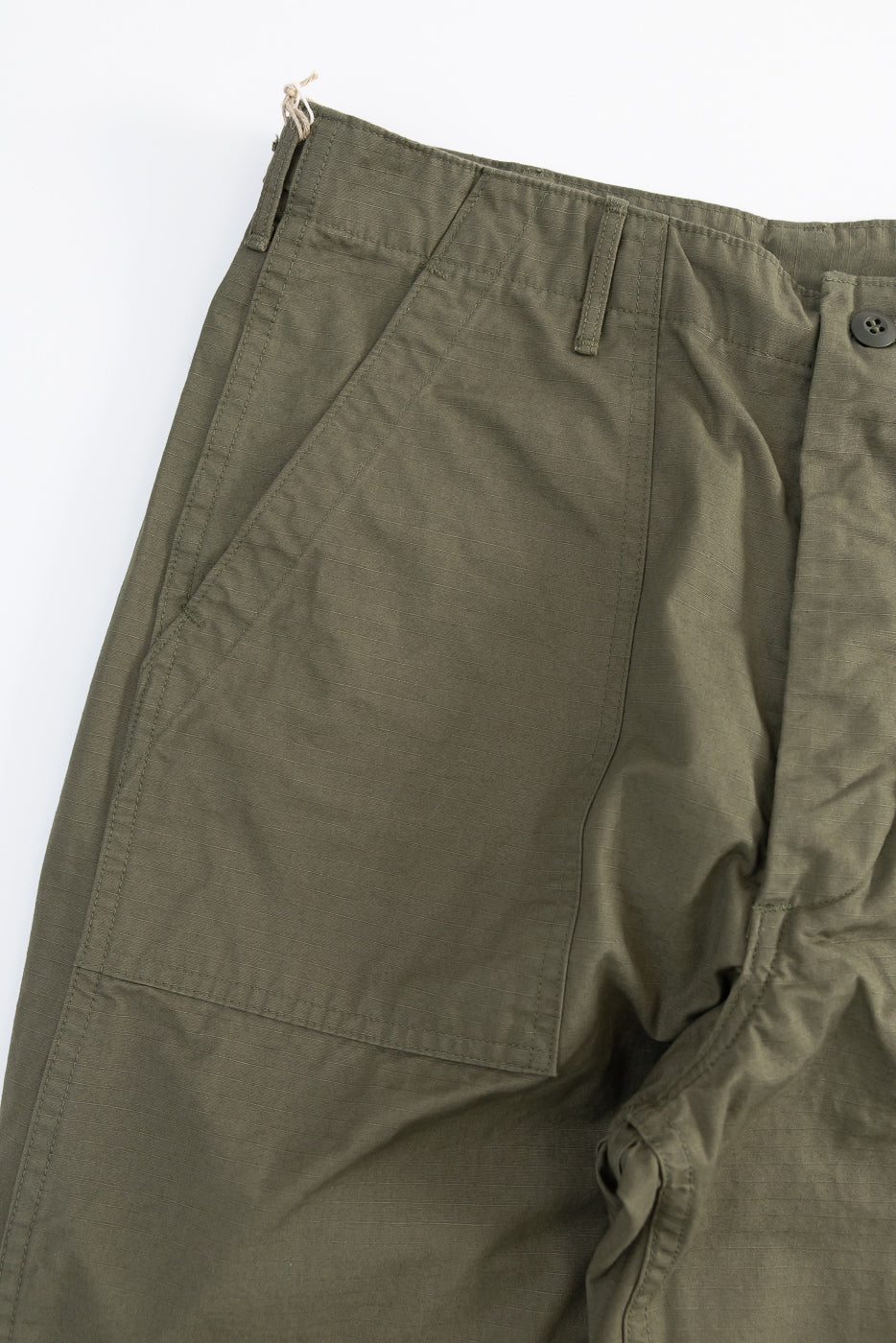 Close-up front view of army green ripstop fatigue pants, highlighting pocket and button details.
