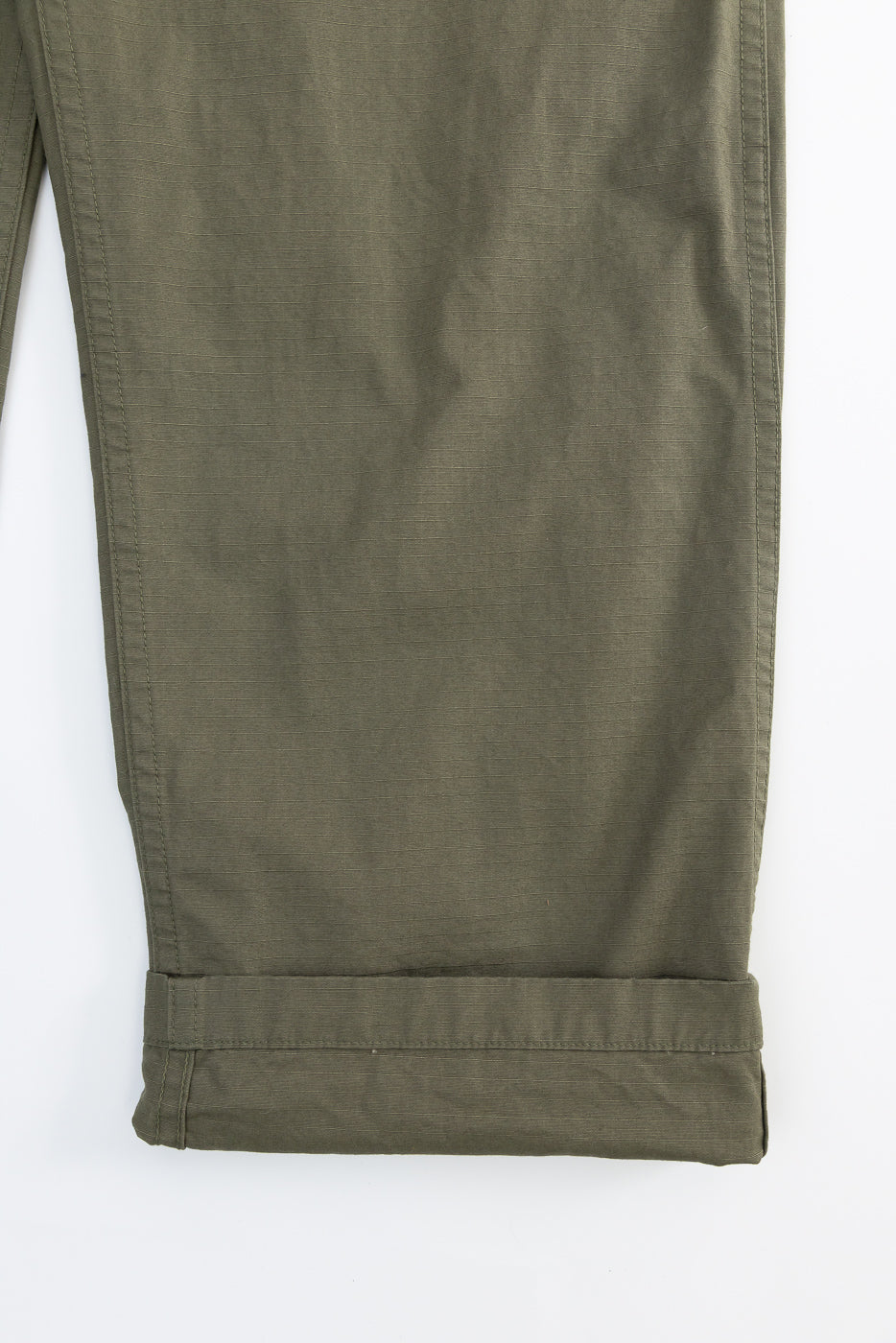 Close-up of front left leg hem on army green ripstop fatigue pants, showing cuff detail and fabric texture.