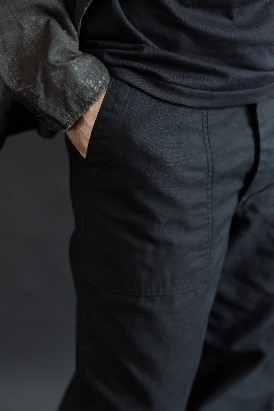 Close-up of front left pocket and upper leg of deep black fatigue pants worn by male model, 5'9