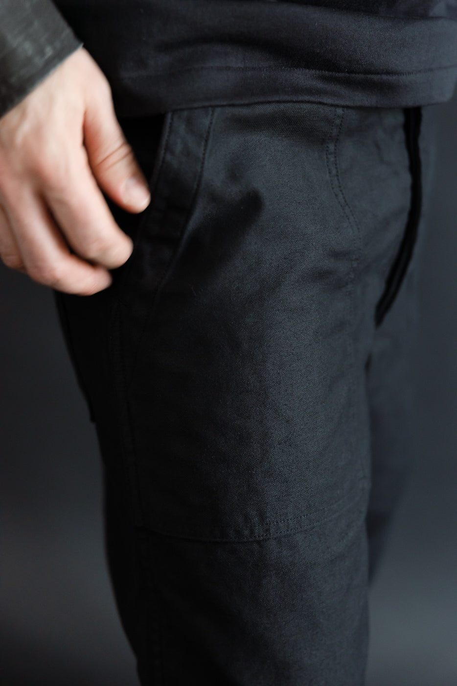Close-up of front left side of deep black reverse sateen fatigue pants on male model, 5'9