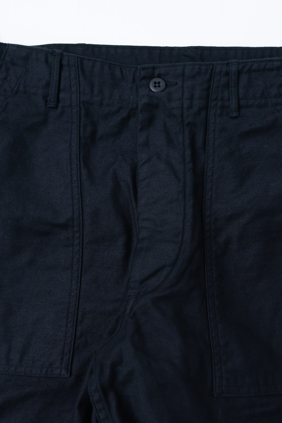 Close-up of front waist and button of deep black reverse sateen fatigue pants, showing fabric texture.