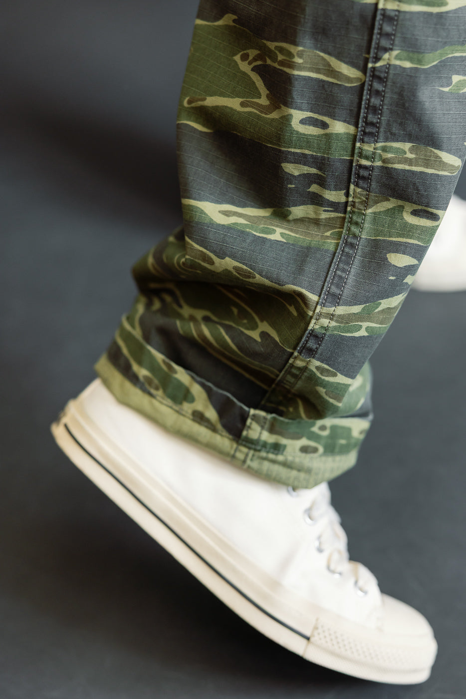 Close-up of the 01-5002-TGC - Fatigue Pants Ripstop Standard Fit - Tiger Camo, showcasing the cuffed ankle and distinctive tiger camo pattern, paired with a white canvas sneaker.