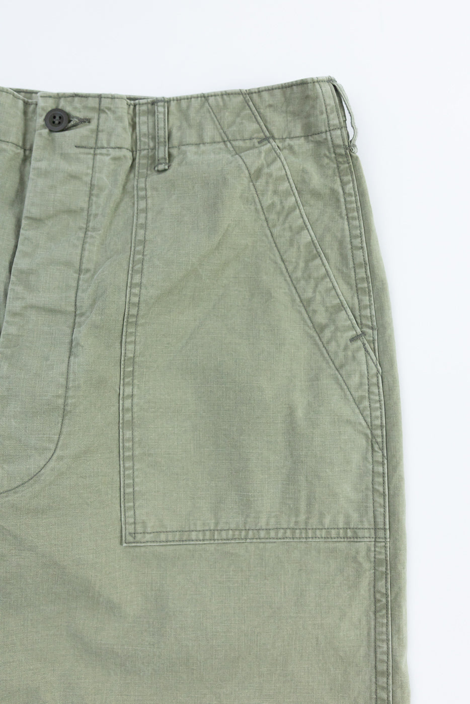 Close-up front view of olive green cargo pants showing button, pocket stitching, and fabric texture