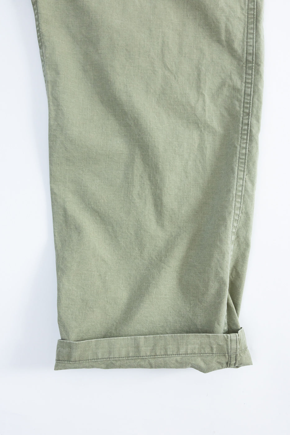 Close-up front view of olive green casual pants with cuffed hem, showing fabric texture and stitching detail