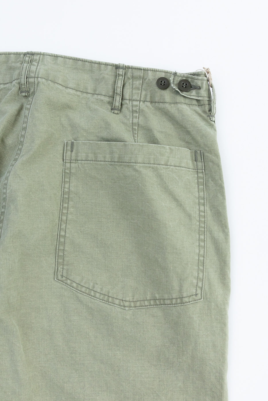 Close-up back view of olive green casual pants showing rear pocket, button closure, and fabric texture