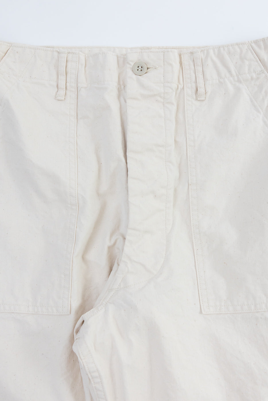 Close-up front view of off-white casual pants showing button fly, belt loops, and fabric texture
