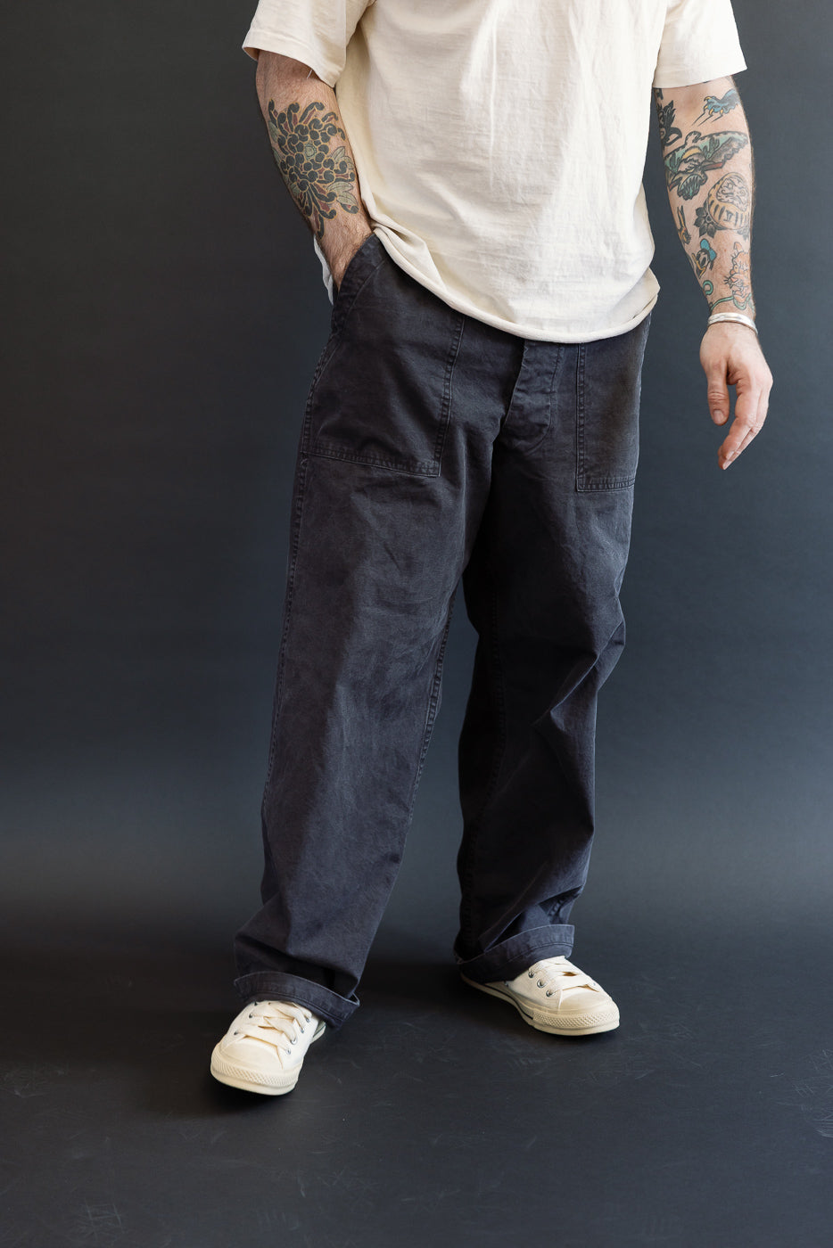 Lower torso view showcasing orSlow 01-5103-M61K Duck Canvas Summer Fatigue Pants in black, featuring a high-rise, wide-leg fit with large front patch pockets, styled with off-white sneakers.