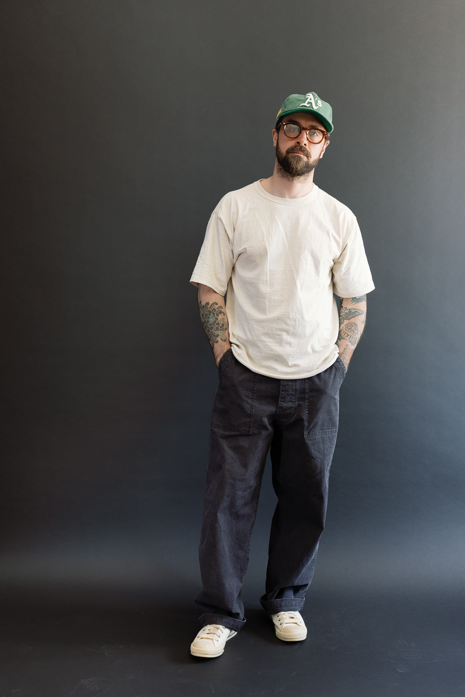 Man wearing orSlow 01-5103-M61K Duck Canvas Summer Fatigue Pants in black, showcasing high-rise, wide-leg fit, styled with casual T-shirt and sneakers, embodying Dant's premium menswear aesthetic.