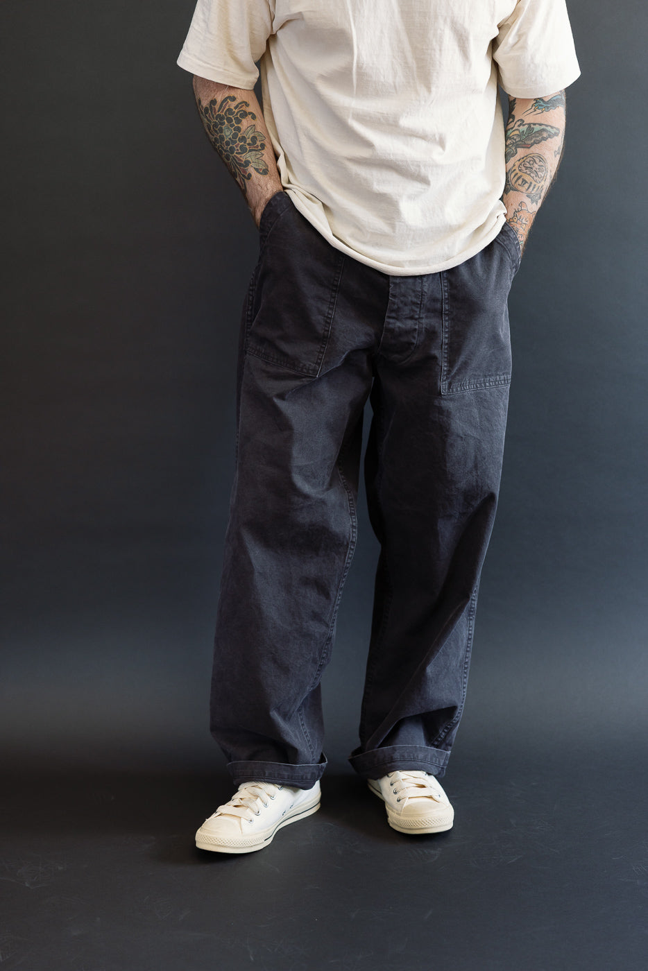 Person wearing orSlow 01-5103-M61K Duck Canvas Summer Fatigue Pants in black, featuring a high rise and wide fit, with visible patch pockets, paired with white canvas sneakers and an off-white T-shirt.