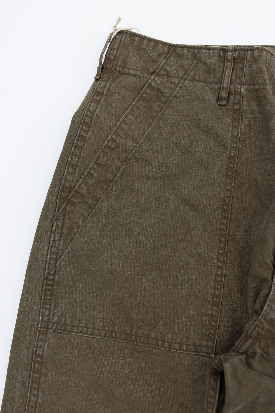 Close-up front view of olive cargo pants showing diagonal pocket stitching, belt loops, and fabric texture