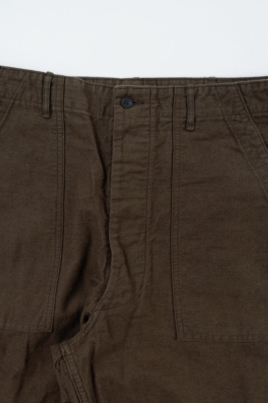 Close-up of front waist and pockets on orSlow coffee brown cotton linen fatigue pants, button detail.