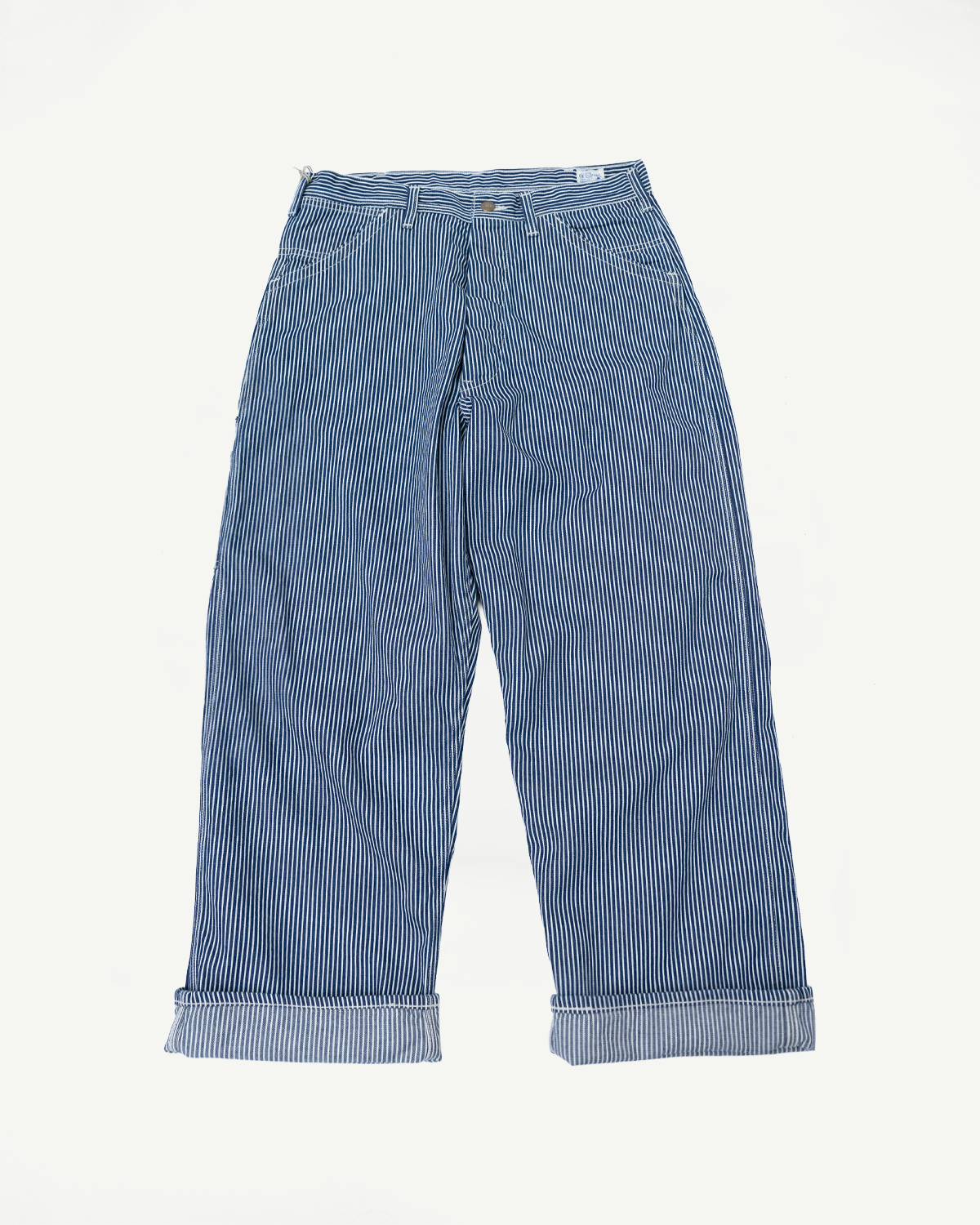 Flat lay, front view of wide-fit indigo ecru hickory painter’s pants, striped, cuffed hem.