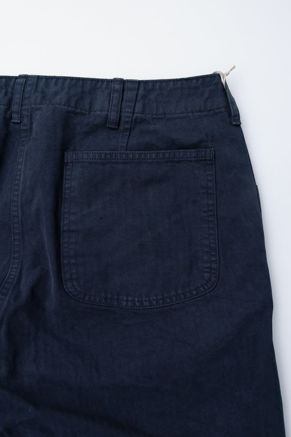 Close-up of back side, upper section of orSlow USMC herringbone utility trousers in black, showing rear pocket and belt loops, fabric detail visible.