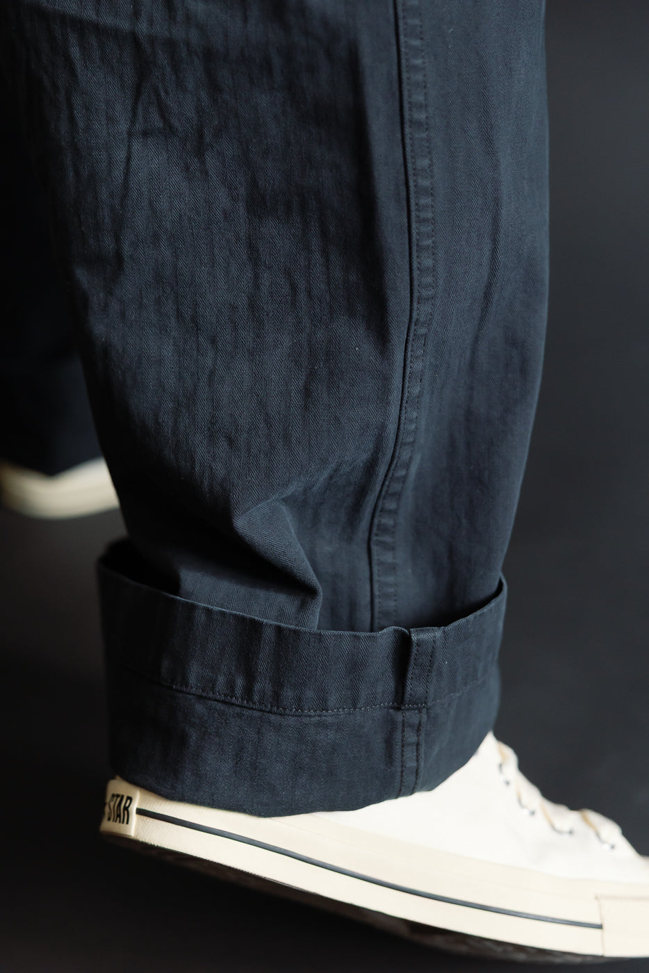 Close-up of orSlow USMC herringbone black utility trousers cuff and fabric texture on male model's lower leg, side view