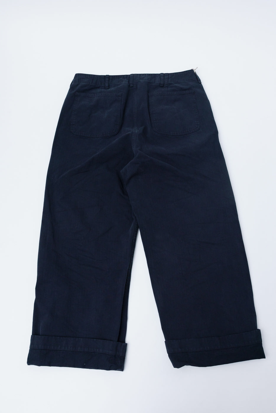 Back view flat lay of orSlow USMC wide fit herringbone utility trousers in black, showing rear pockets and cuffed hems from Dant contemporary apparel.