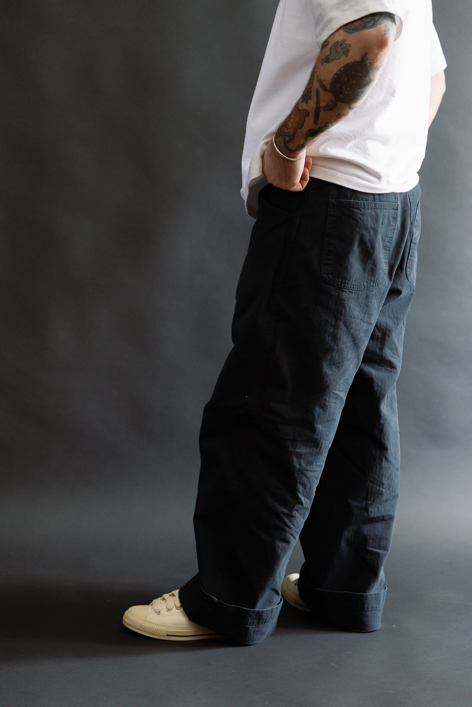 Male model 5'9 165lbs athletic build, side view close-up, black wide fit utility trousers, visible back pocket