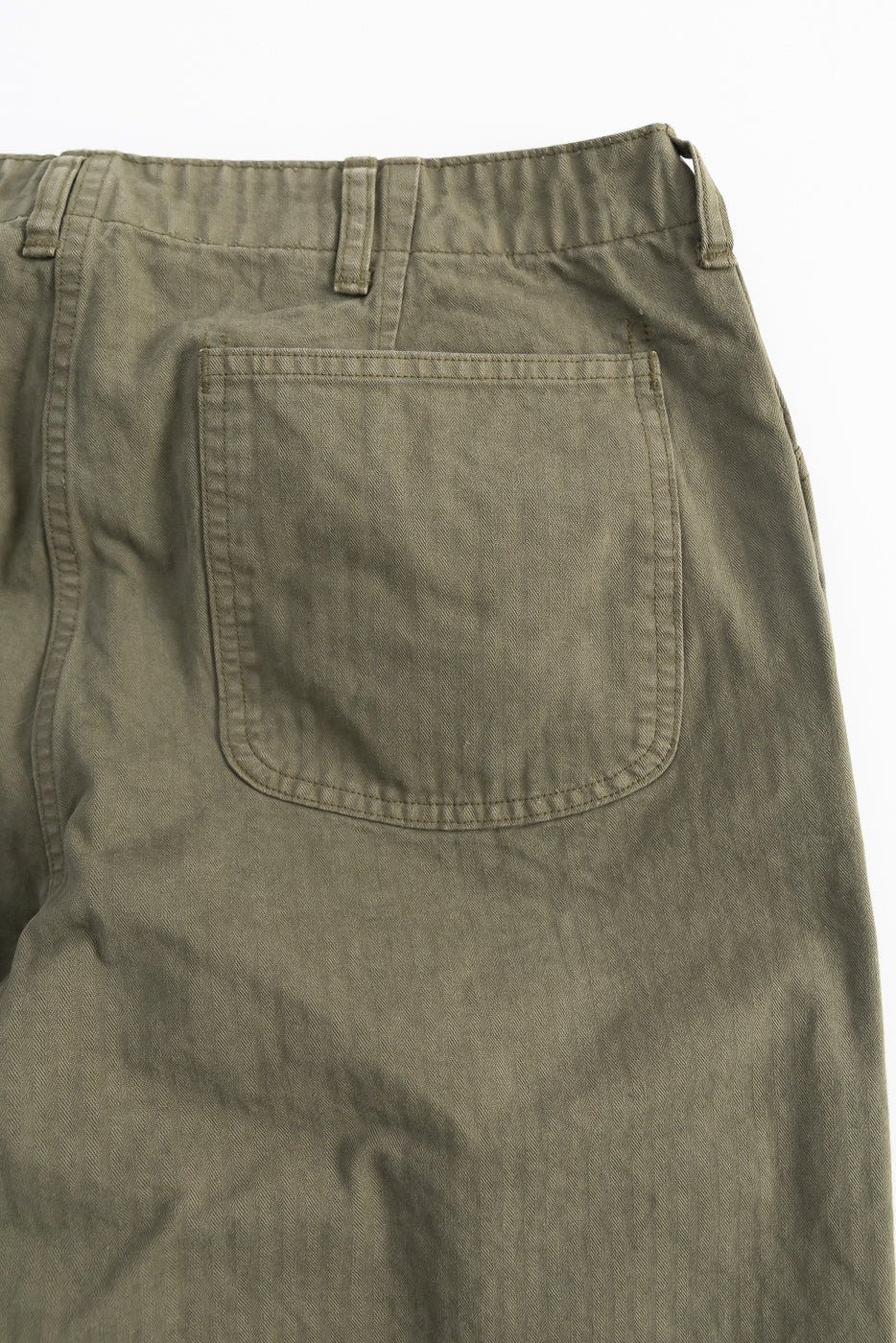 Close-up of back pocket and herringbone fabric on orSlow USMC utility trousers in dark olive, rear view