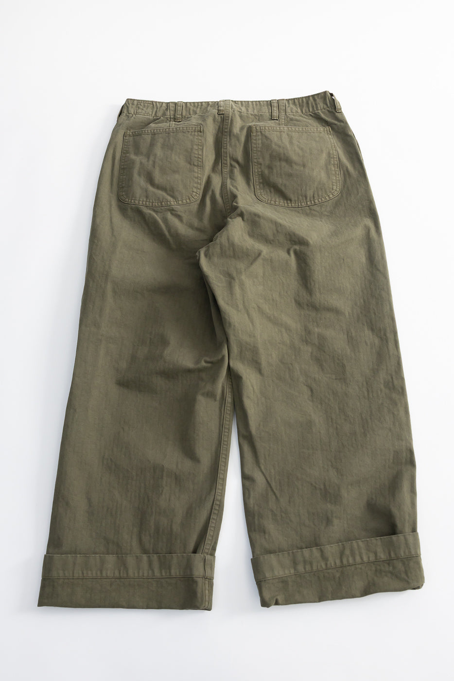 Back view flat lay of orSlow USMC herringbone wide fit utility trousers in dark olive, showing rear pockets and cuffed hems.