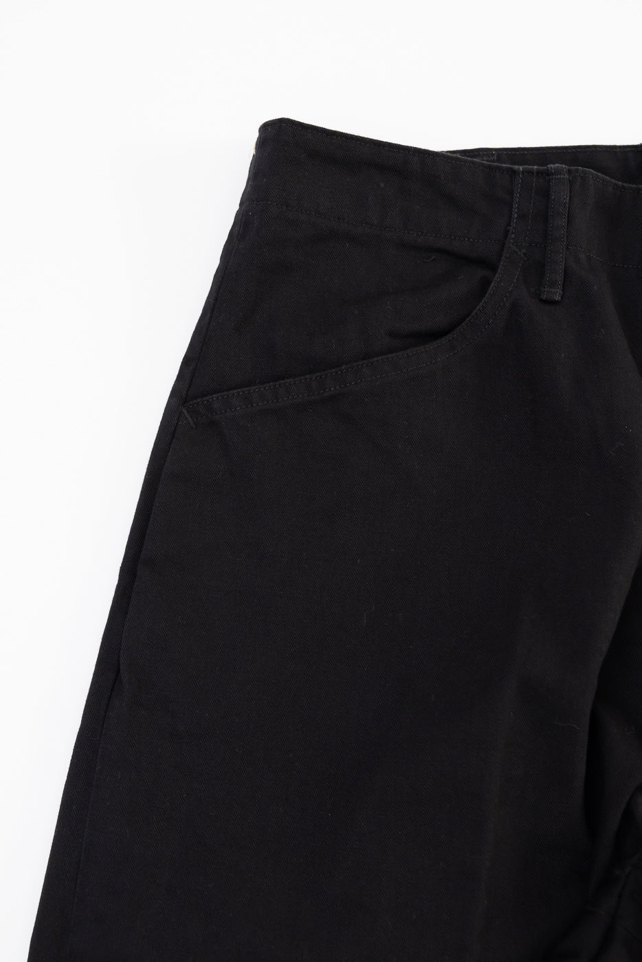 Close-up front view of black cotton trousers showing waistband and pocket detail.