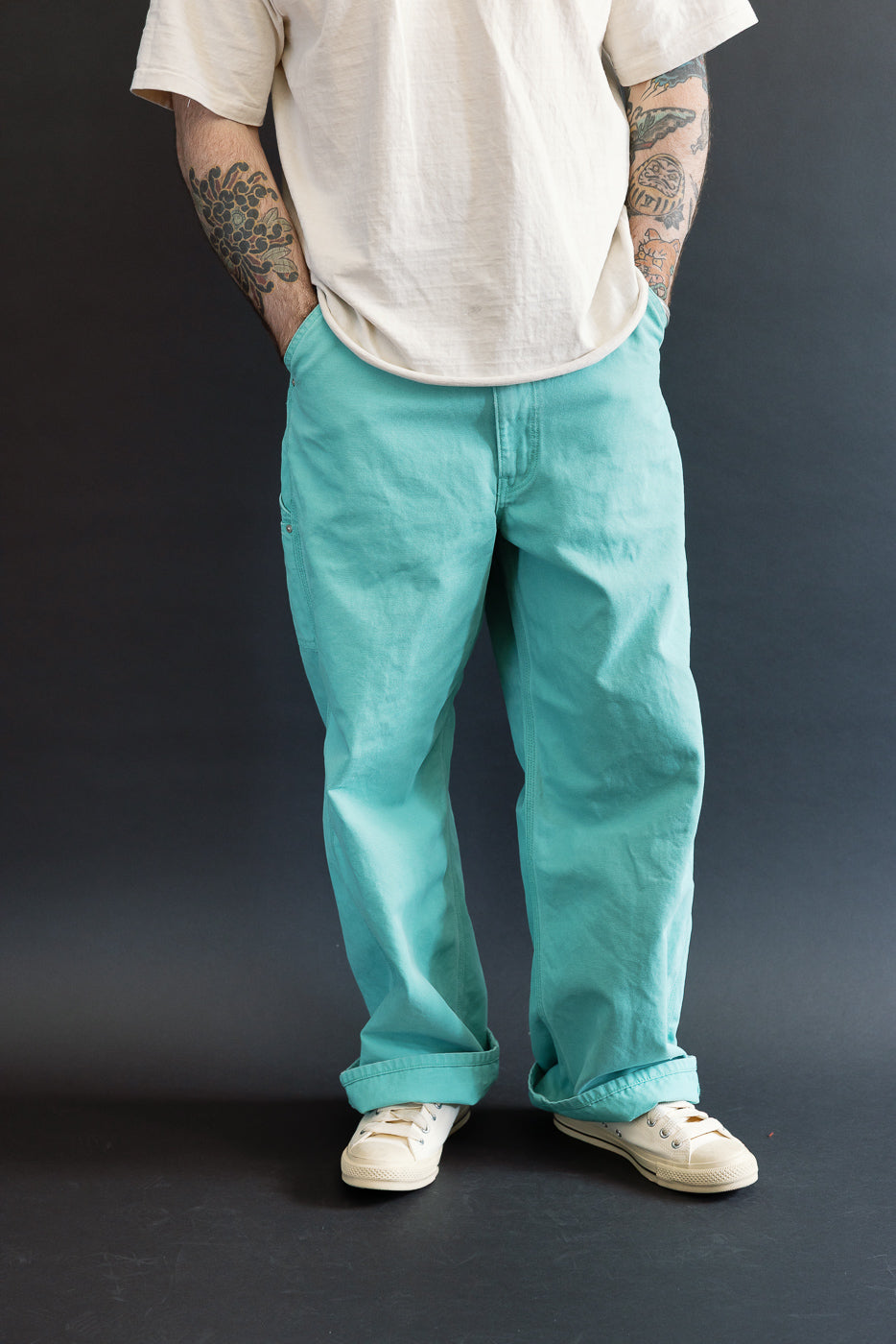 01-5328-39SK - Dad's Fit Painter's Pants Canvas - Turquoise, featuring a relaxed fit with rolled cuffs and visible brass UFO rivet detail, styled with off-white sneakers against a dark backdrop.