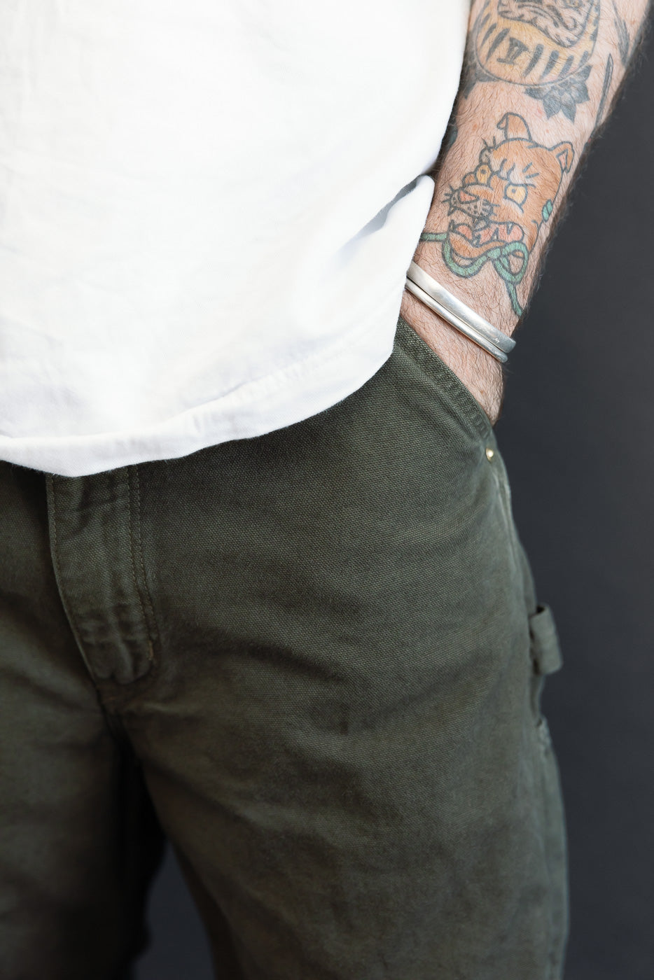 Close-up side view of olive green utility pants worn by a male model, 5'9