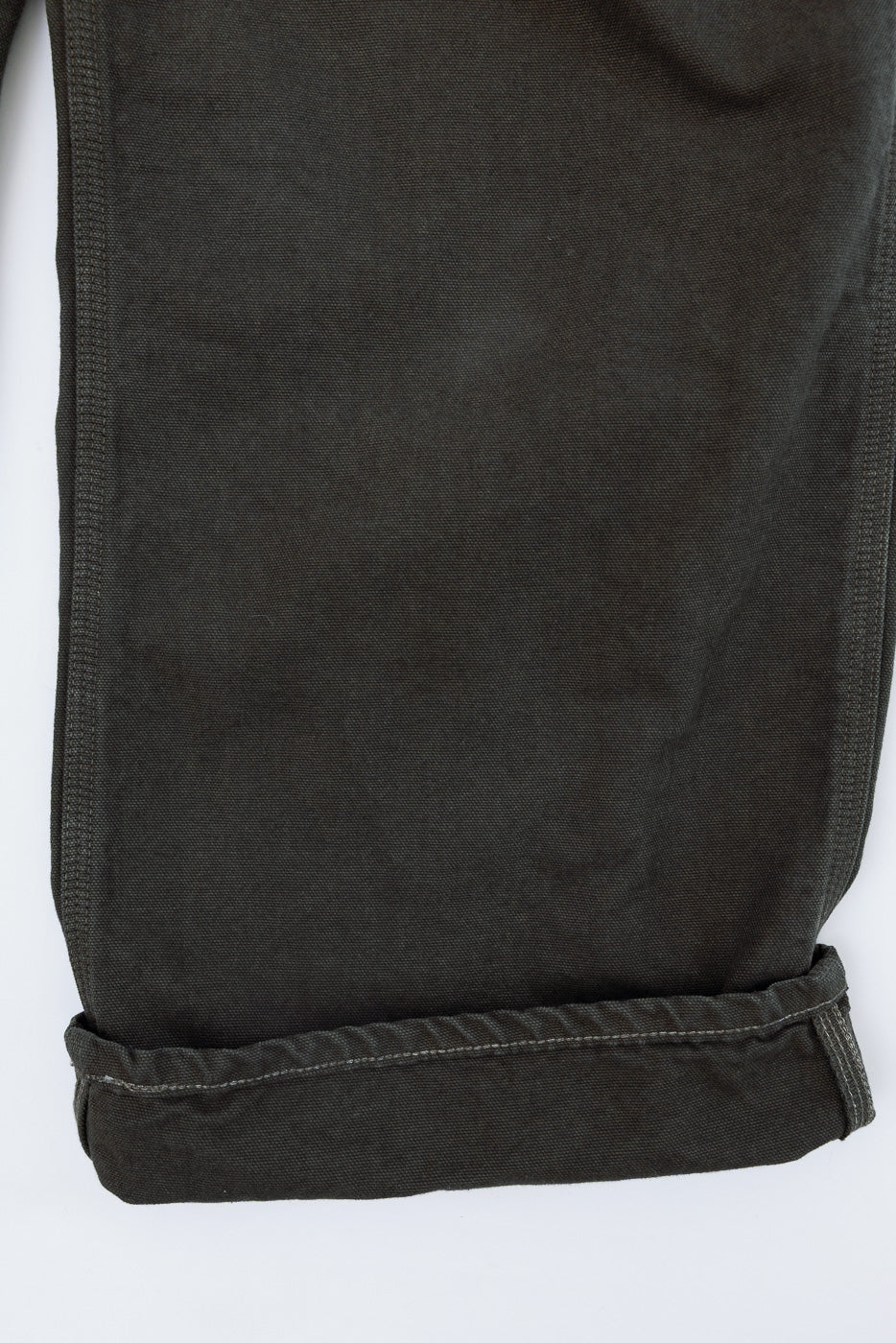 Close-up of the cuffed hem on the side of dark grey casual trousers.
