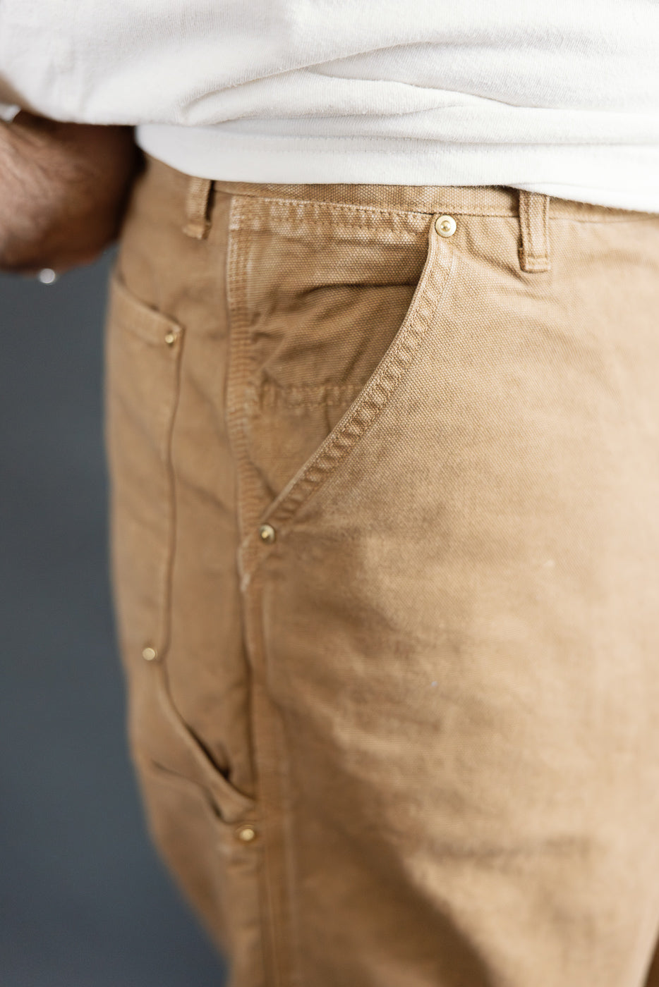 Close-up side view of orSlow brown canvas painter pants front pocket on male model, 5'9