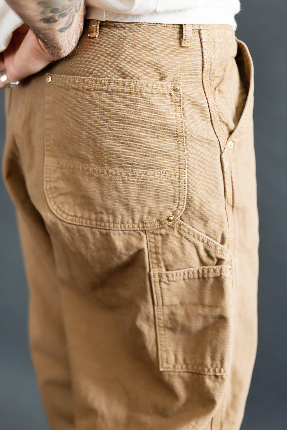 Close-up of back and side pockets on brown canvas men's painter pants, right rear view, male model 5'9