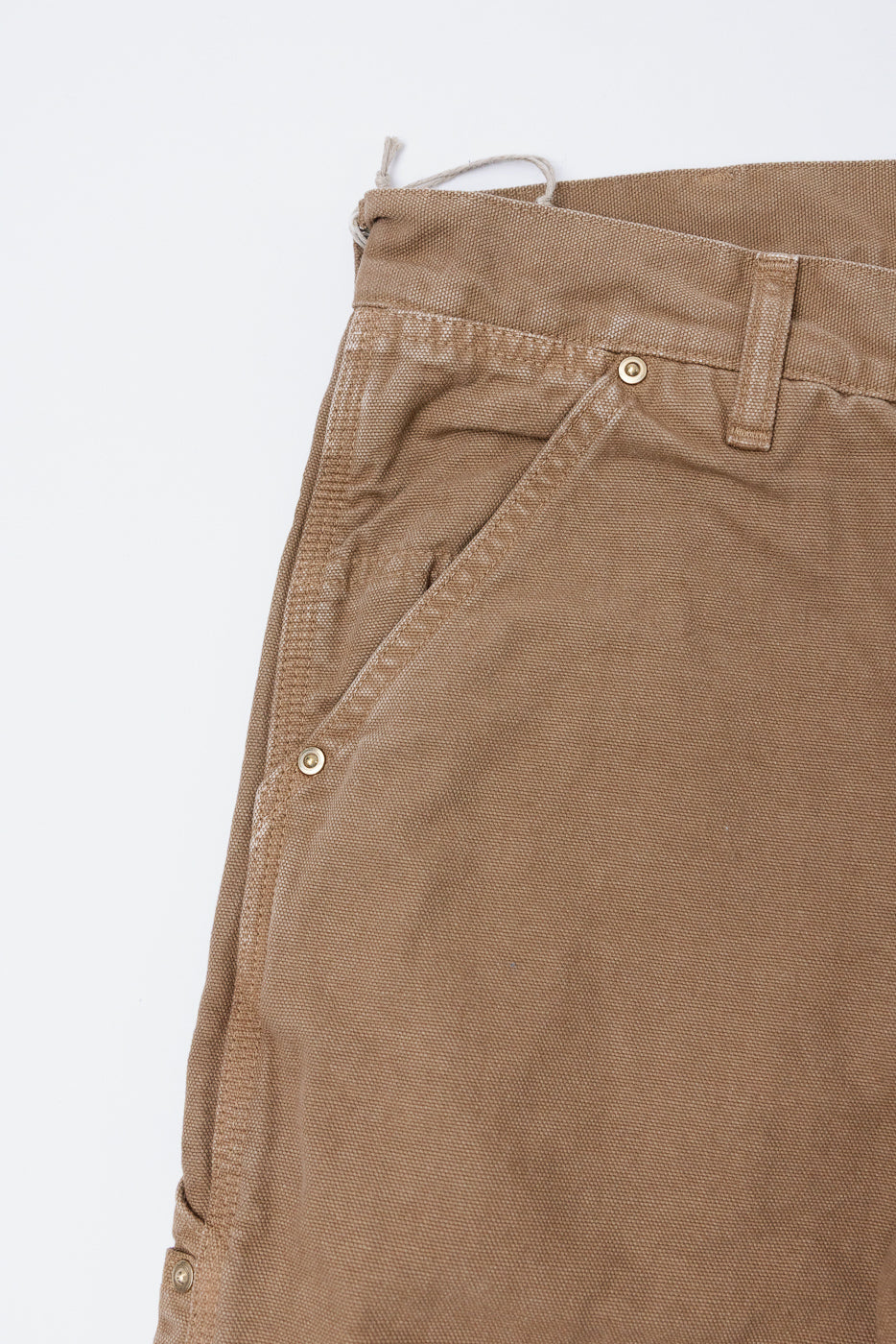 Close-up of front left side orSlow Dad's Fit painters pants in brown canvas, showing pocket, rivets, and textured fabric.