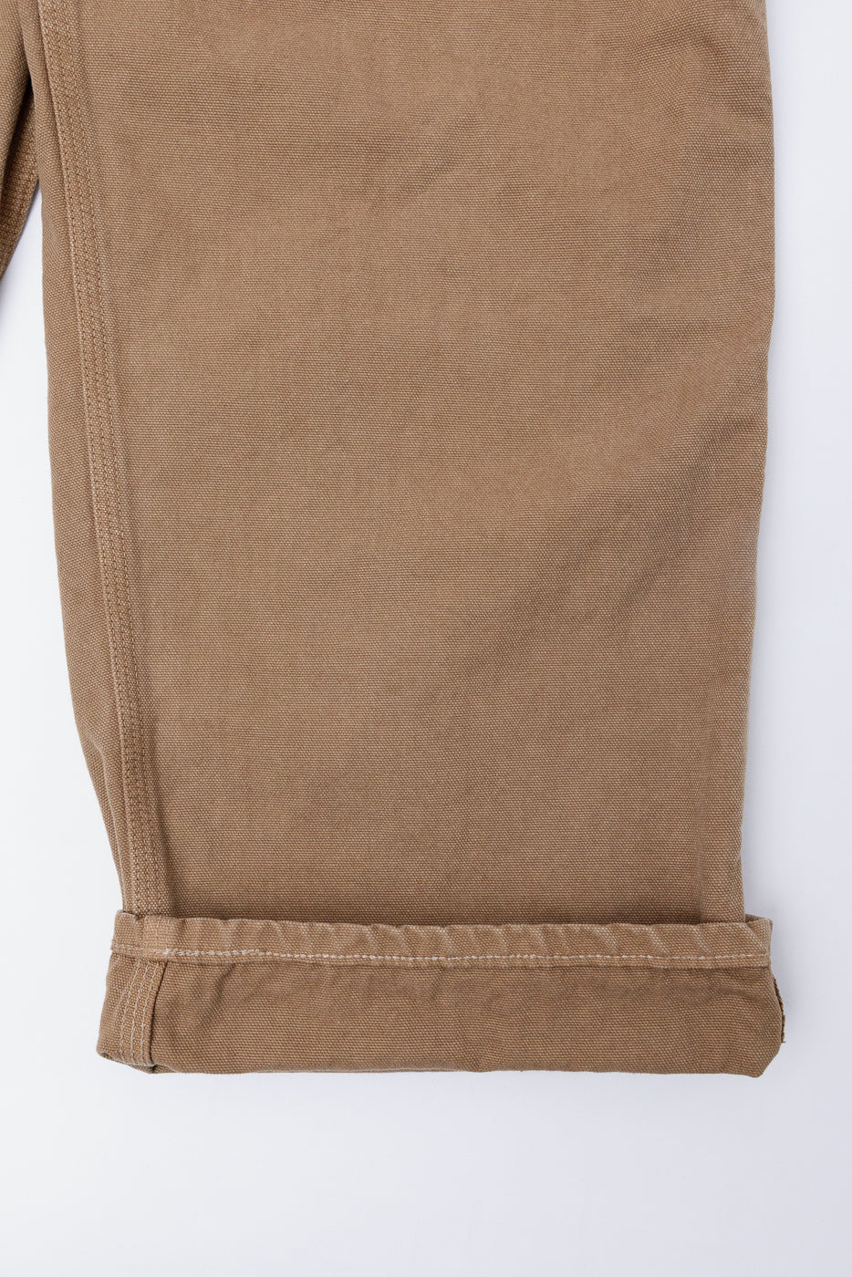 Close-up of orSlow brown canvas painter pants cuff, shows fabric texture and hem stitching, side view