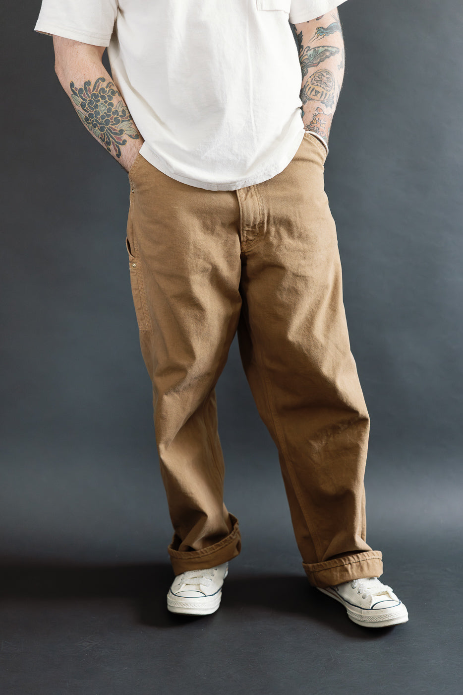 Front view, mid-body of male model 5'9, 165lbs, athletic build, wearing brown canvas painter's pants by Dant.