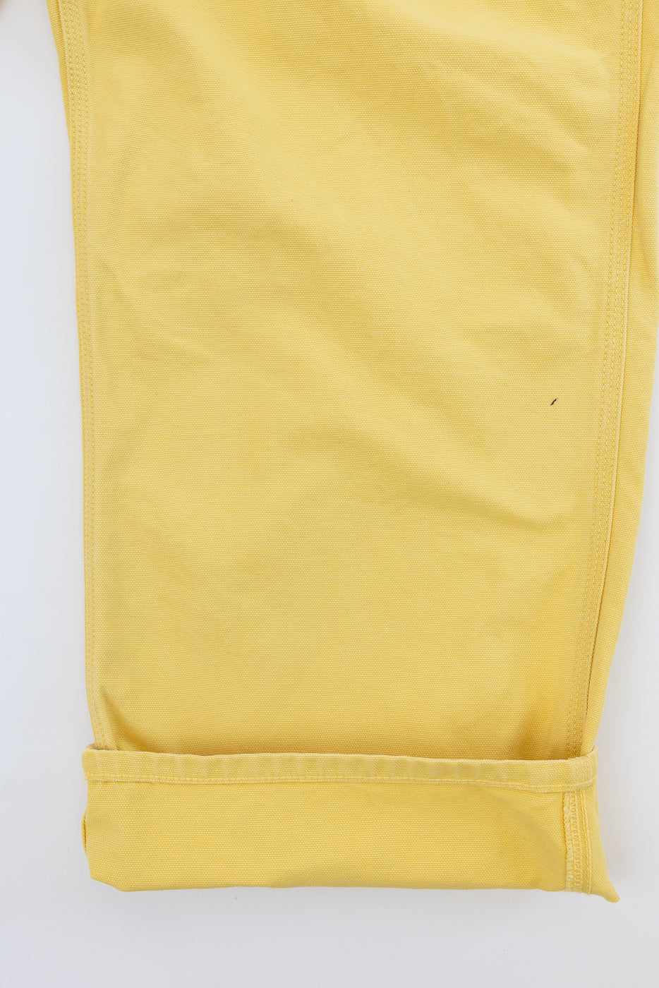 Close-up front view of mustard yellow casual pants, showing cuffed hem and fabric texture