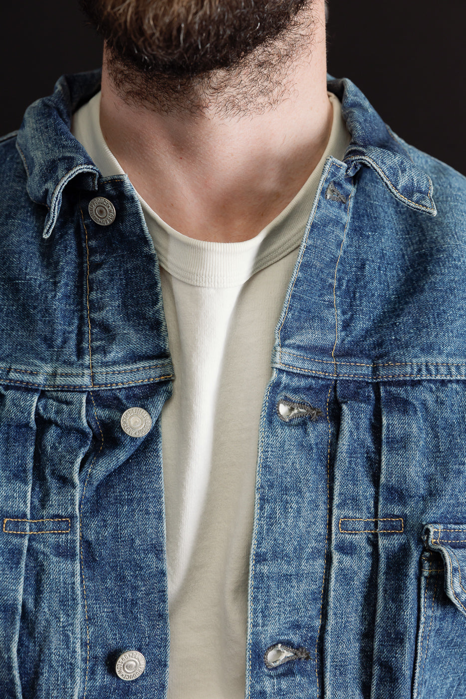 Close-up front view of a blue denim jacket showing button details and fabric texture.