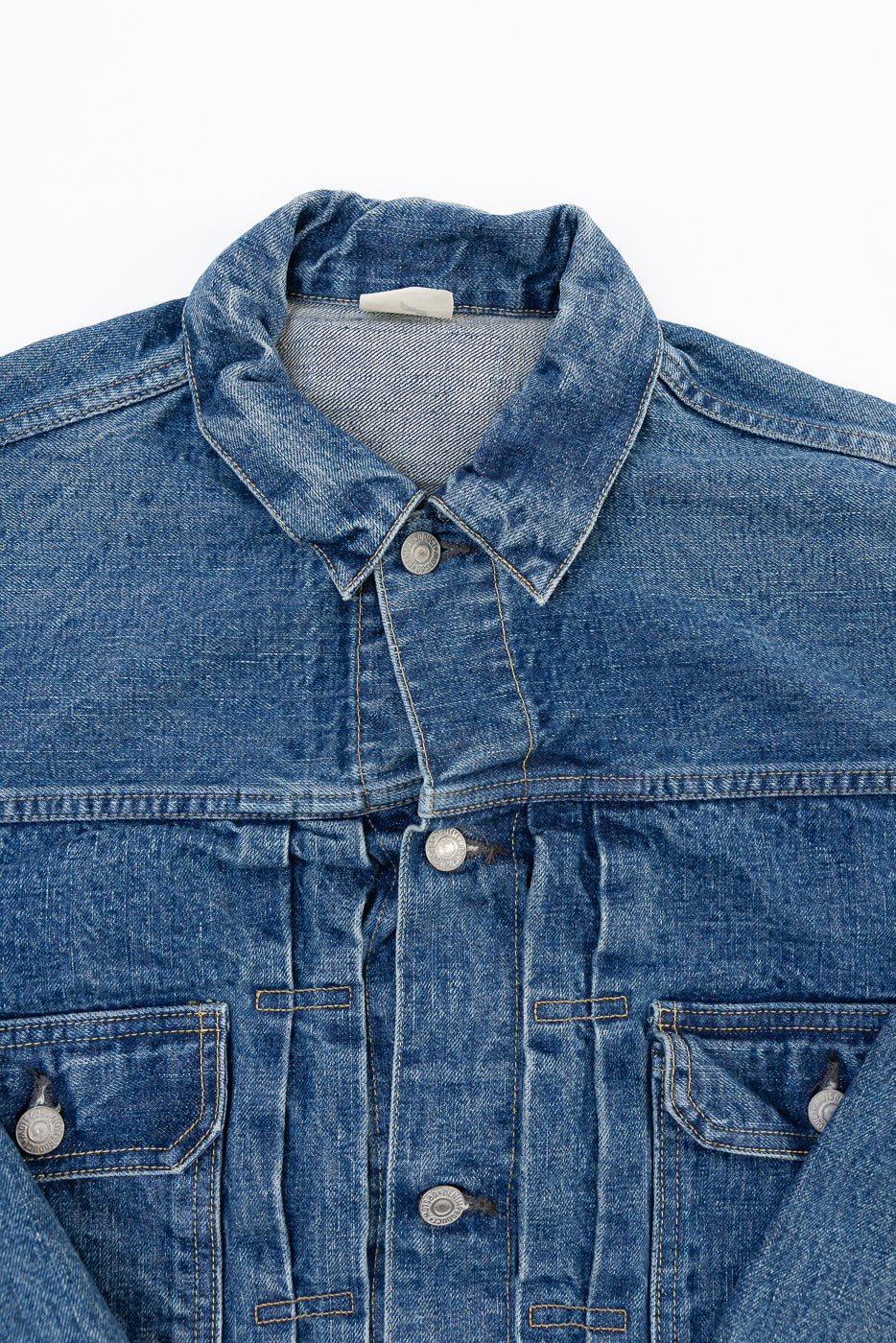 Close-up front view of a blue denim jacket showing the collar, buttons, and fabric texture.