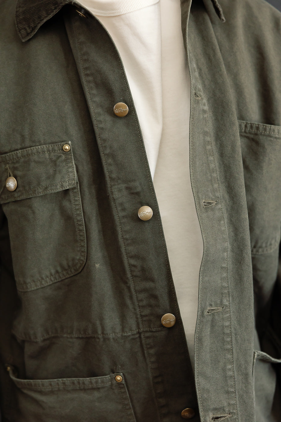 Close-up front view of an olive green button-down shirt showing fabric texture and buttons.