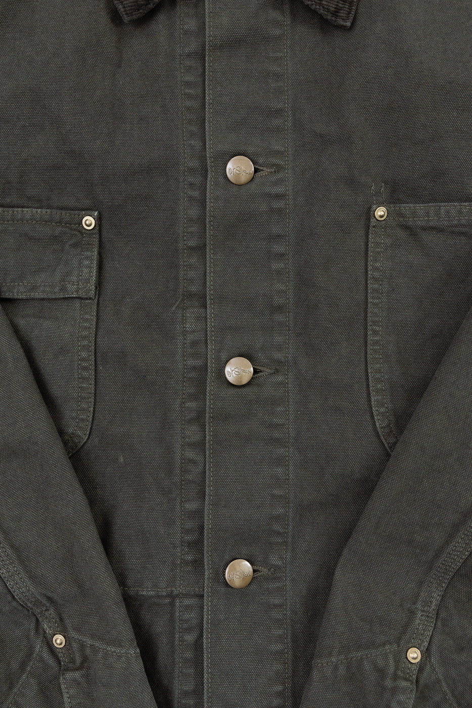 Close-up of the front of a dark grey jacket showing fabric texture and metallic buttons.