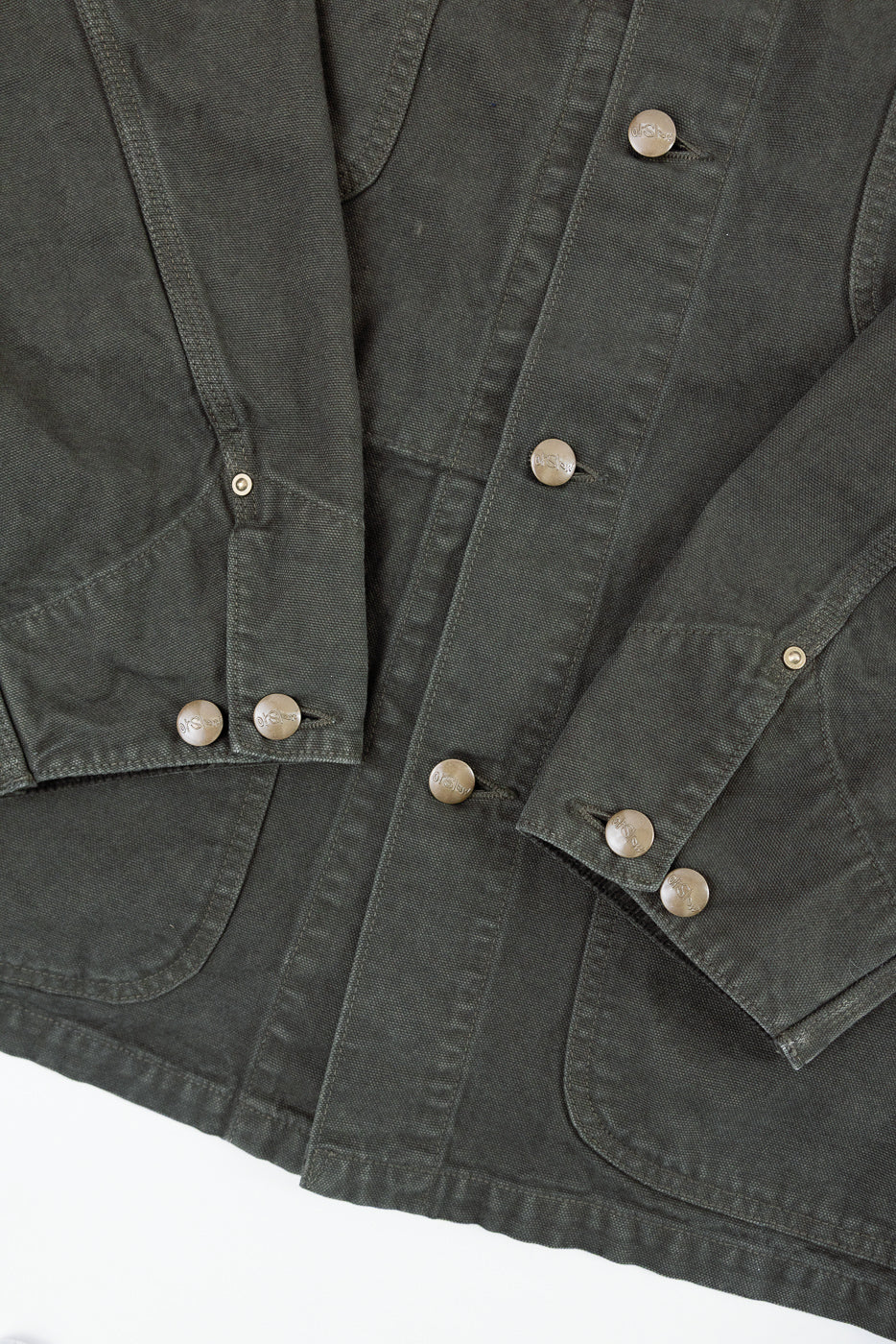 Close-up front view of olive green canvas jacket showing button details and fabric texture.