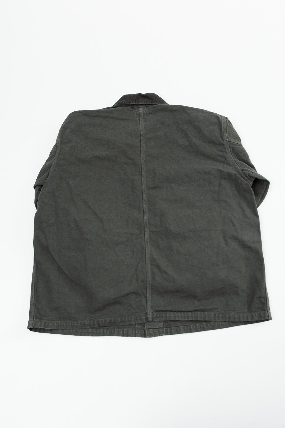 Back view flat lay of a dark olive green canvas chore coat showing seam details.