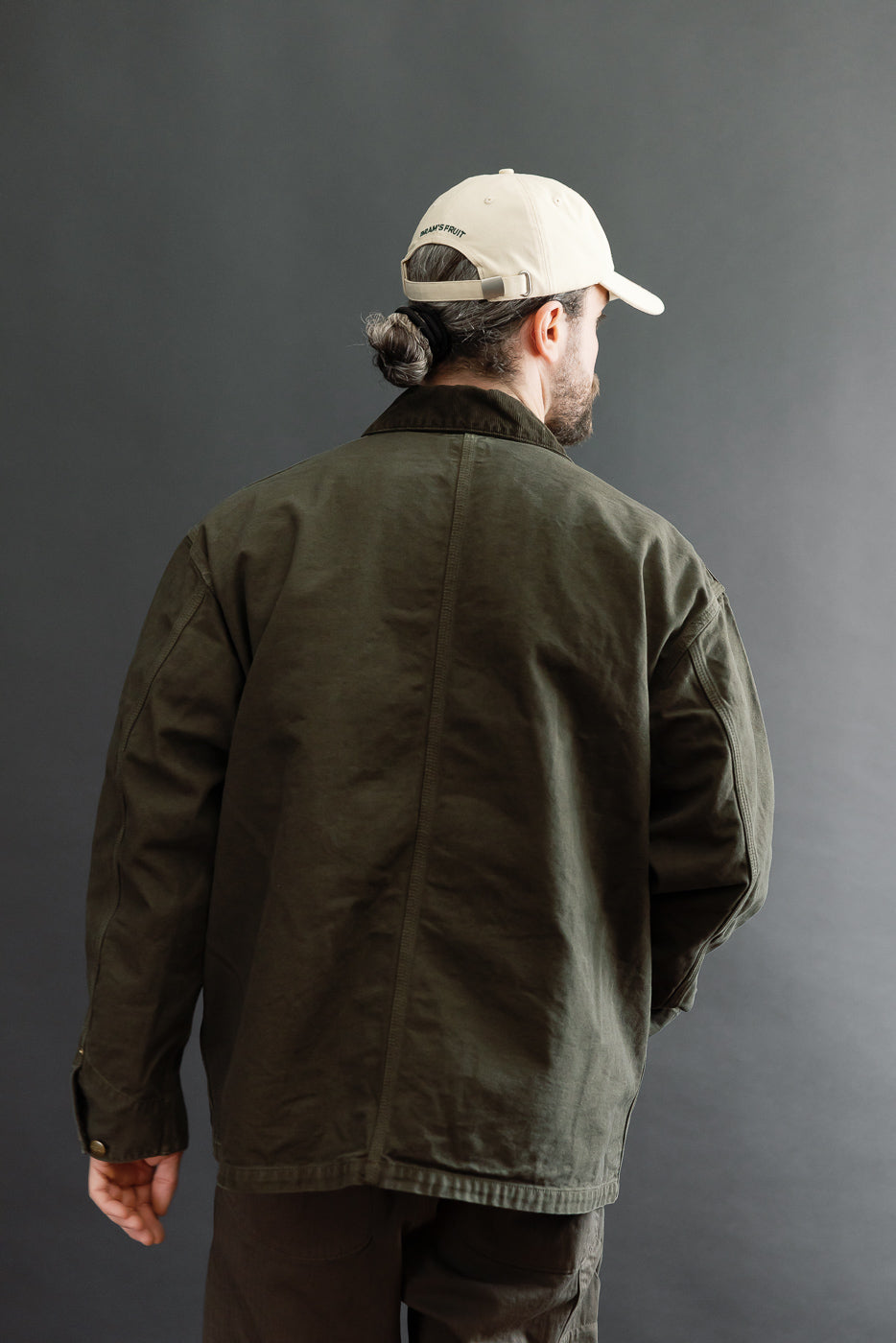 Back view of an olive green canvas jacket on a 5'9