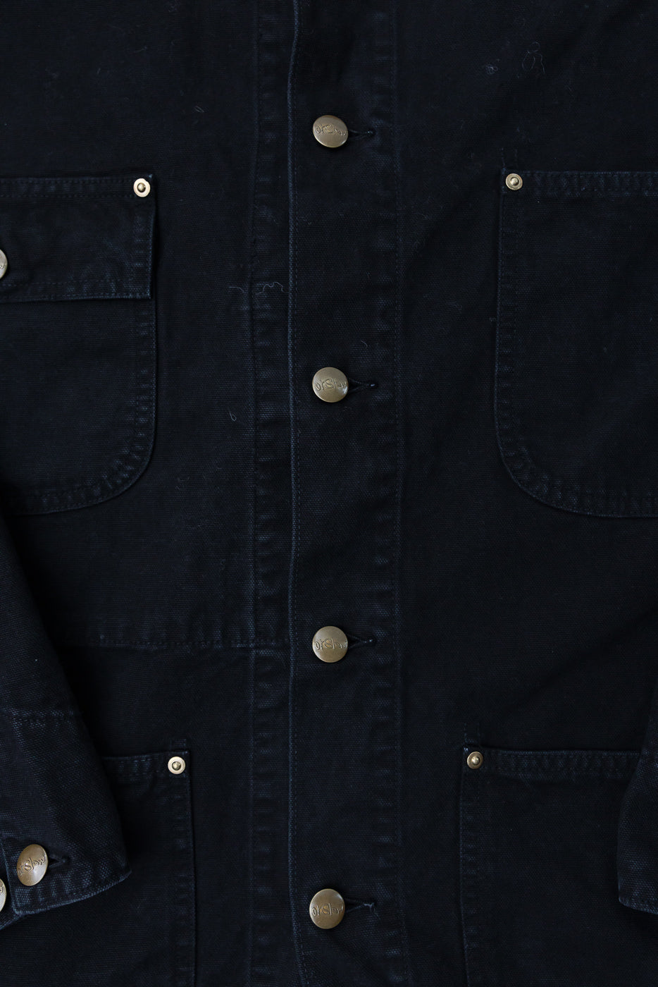 Close-up front view of orSlow relaxed fit black coverall jacket showing brass buttons and front pockets, Dant contemporary apparel