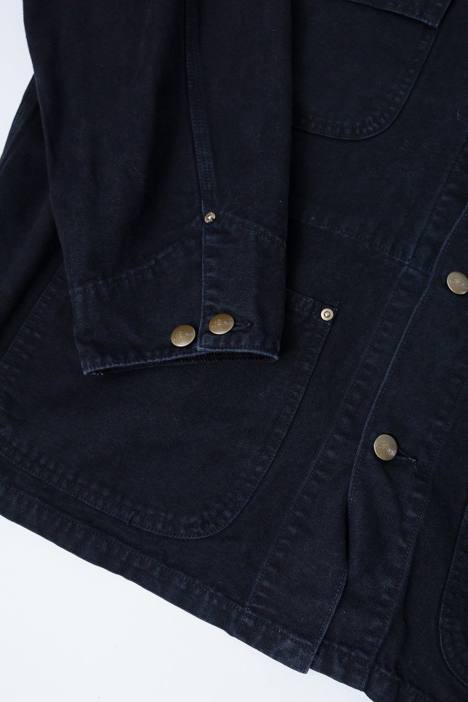 Close-up of orSlow black coverall jacket front, snap buttons, sleeve cuff, front pocket detail